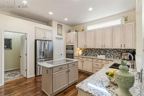 a kitchen with granite countertop a sink stove and refrigerator