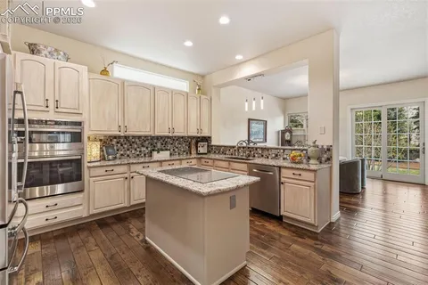 a kitchen with stainless steel appliances granite countertop a stove cabinets and wooden floor