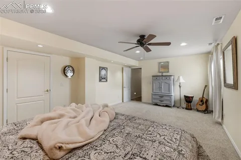 a spacious bedroom with a bed a couch and a chandelier