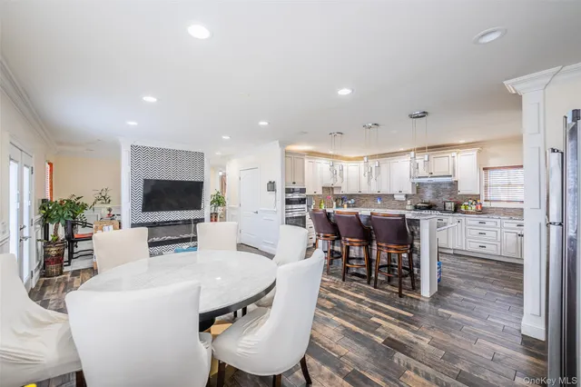 a living room with stainless steel appliances furniture a flat screen tv and a kitchen view