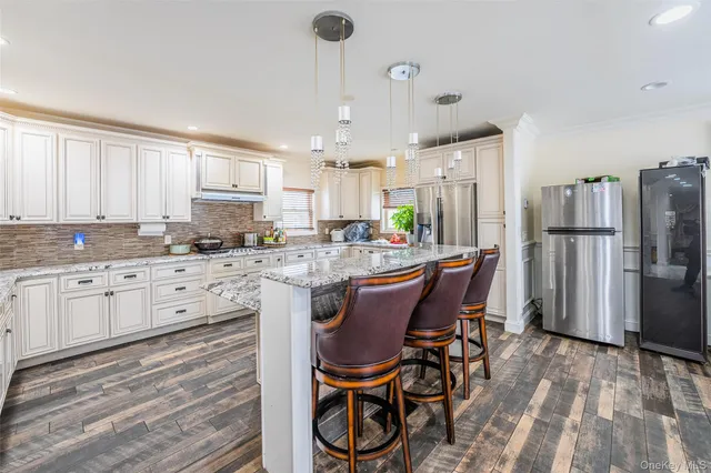 a kitchen with stainless steel appliances granite countertop a refrigerator a stove a sink dishwasher and white cabinets with wooden floor