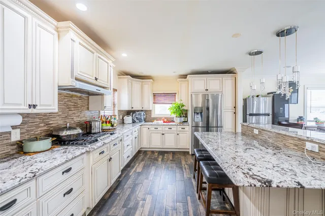 a kitchen with stainless steel appliances granite countertop a lot of counter space and wooden floors