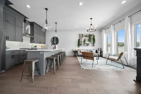 a living room with stainless steel appliances kitchen island a table and chairs in it