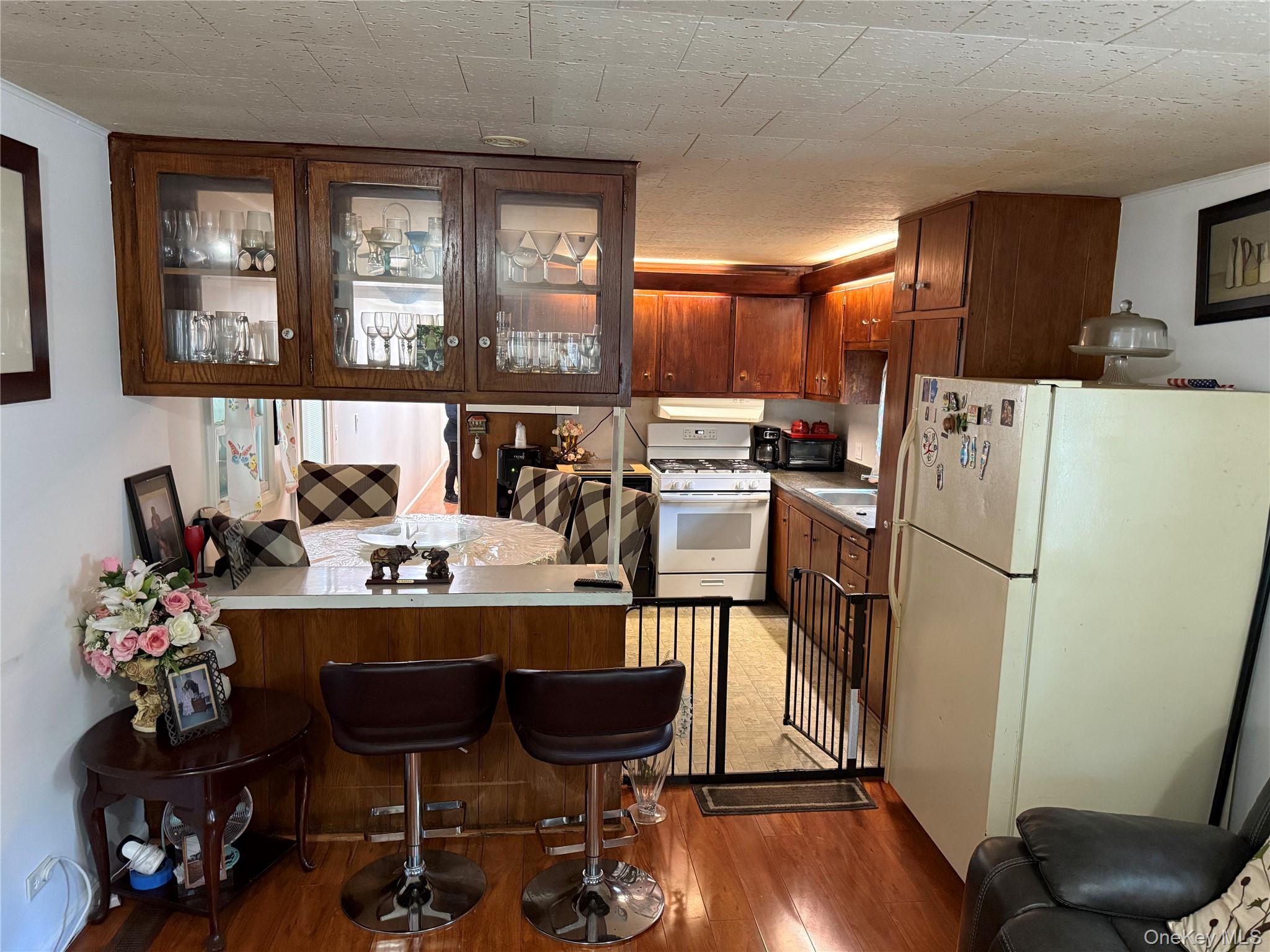 136 Quaker Rd Park Pomona, NY 10970 - Photo 12 of 24 Kitchen featuring wood-finish cabinetry, a white gas range, and a breakfast bar with built-in overhead glass-front cabinets