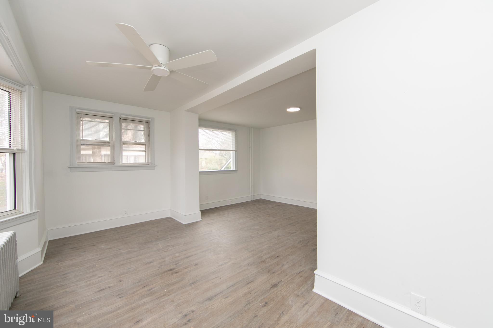 an empty room with wooden floor fan and windows
