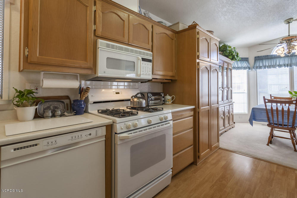 15750 Arroyo Drive, Unit 32 Moorpark, CA 93021 - Photo 15 of 26 a kitchen with stainless steel appliances granite countertop a stove a sink dishwasher and a refrigerator with wooden floor