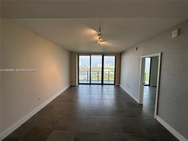 an empty room with large windows and chandelier fan