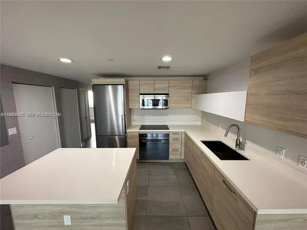 a large kitchen with stainless steel appliances kitchen island a large counter top a stove and a refrigerator