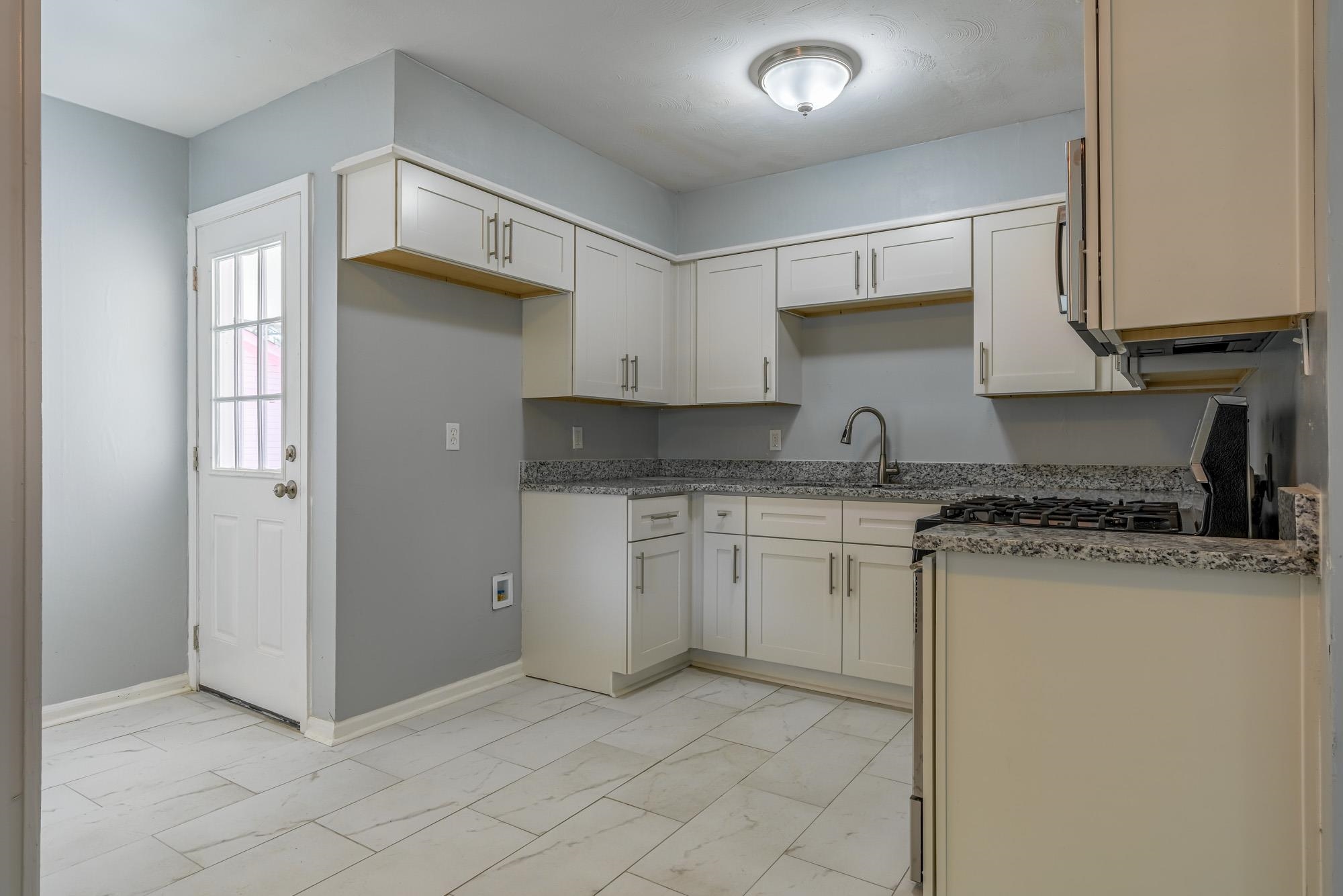 4606 Tulane Road Memphis, TN 38109 - Photo 11 of 25 a kitchen with granite countertop a sink a stove a refrigerator and white cabinets