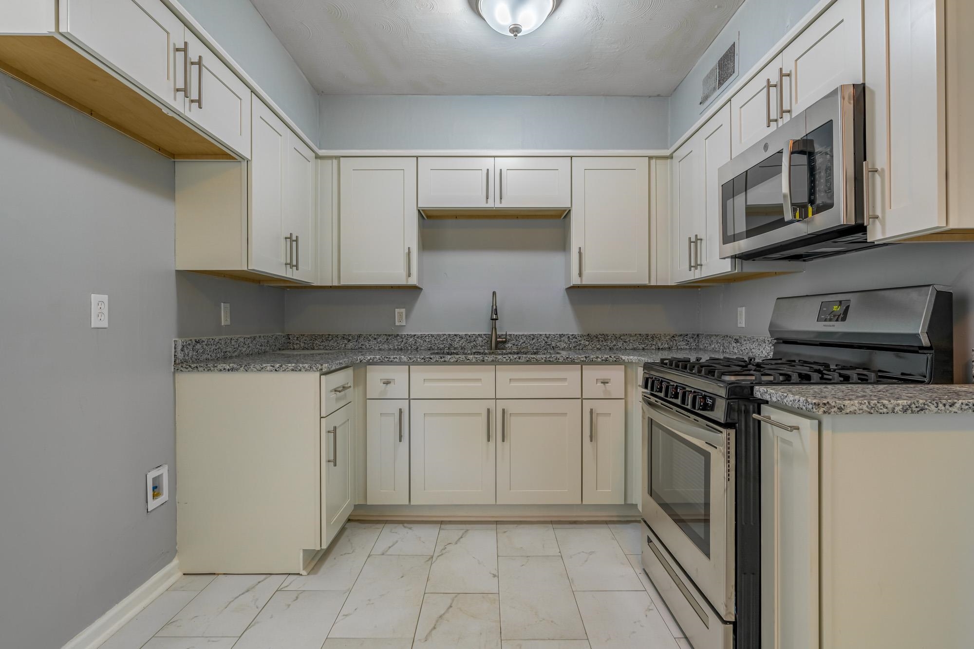 4606 Tulane Road Memphis, TN 38109 - Photo 12 of 25 a kitchen with stainless steel appliances granite countertop a stove a sink and a microwave