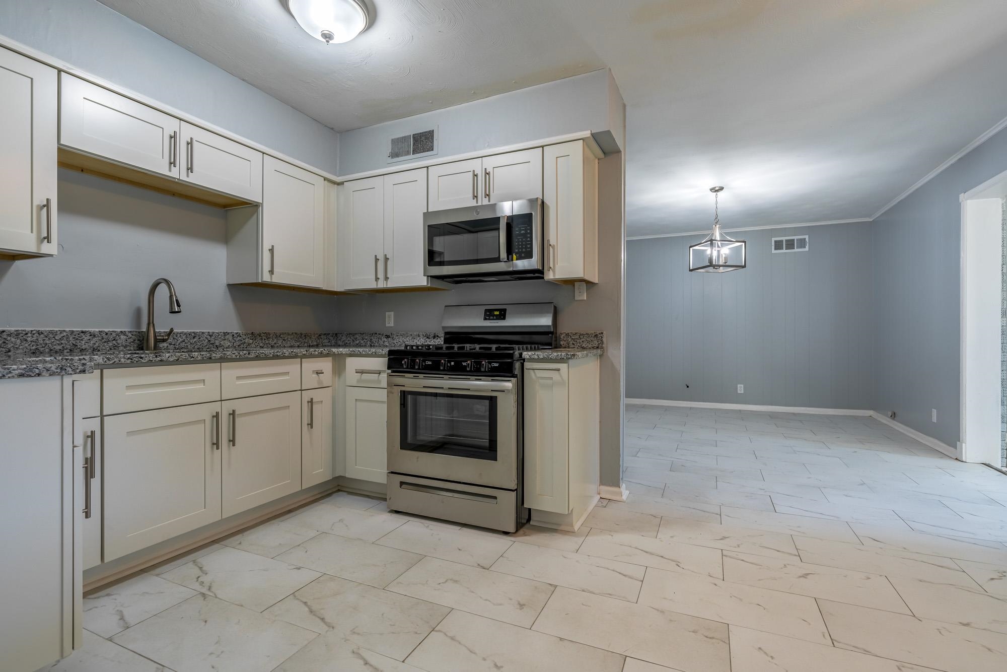 4606 Tulane Road Memphis, TN 38109 - Photo 15 of 25 a kitchen with granite countertop white cabinets stainless steel appliances and sink
