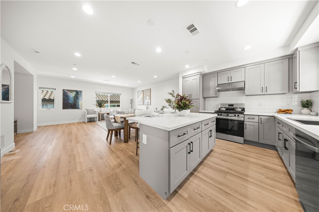 7692 9th Street, Unit 113 Buena Park, CA 90621 - Photo 14 of 41 a large kitchen with stainless steel appliances granite countertop a large counter top a sink a stove and chairs with wooden floor