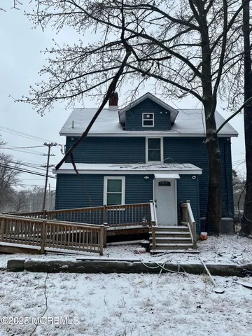 a front view of a house with large trees