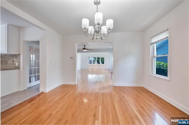 a view of a room with wooden floor chandelier and windows