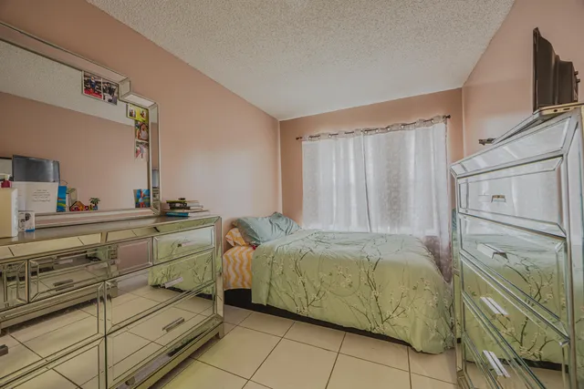 a bedroom with a bed and a flat tv screen on the dresser
