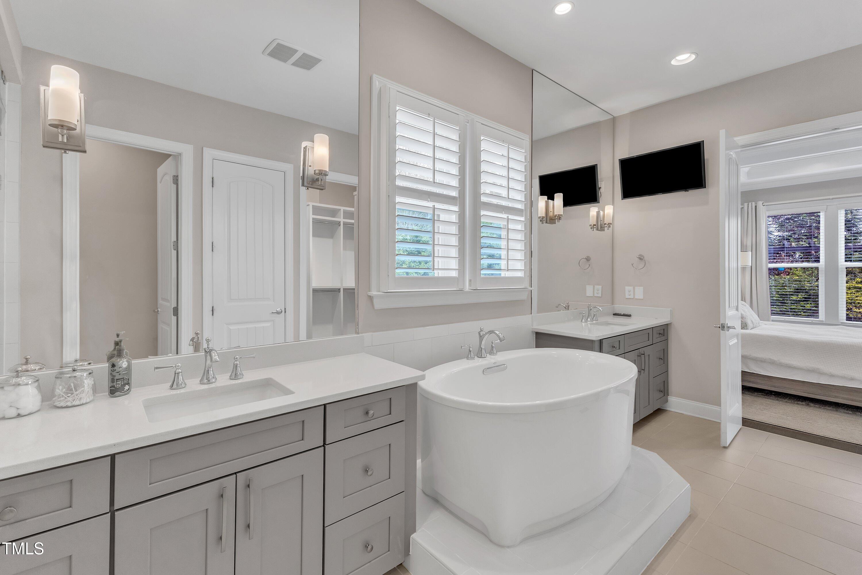 8121 Greys Landing Way Raleigh, NC 27615 - Photo 36 of 95 a bathroom with a double vanity sink a mirror a bathtub and shower