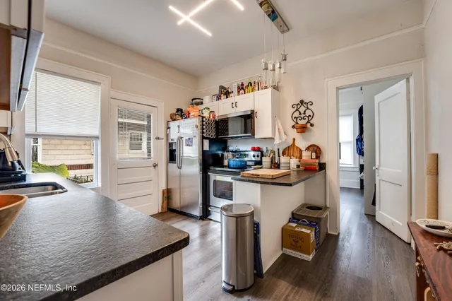 a kitchen with a sink a stove and chairs with wooden floor