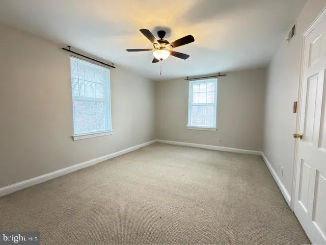 an empty room with window and ceiling fan