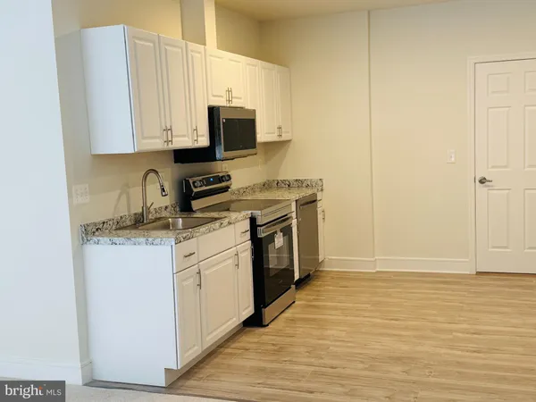 a kitchen with stainless steel appliances granite countertop a stove a sink and a microwave