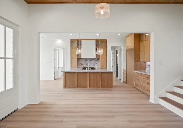 a large kitchen with a refrigerator and wooden floor