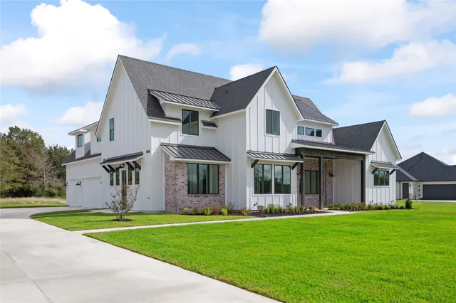 a view of a white house with a big yard and large trees
