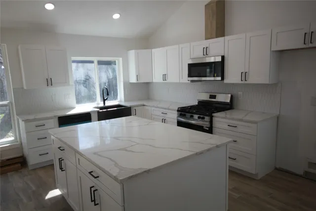 a kitchen with granite countertop a sink stove and microwave