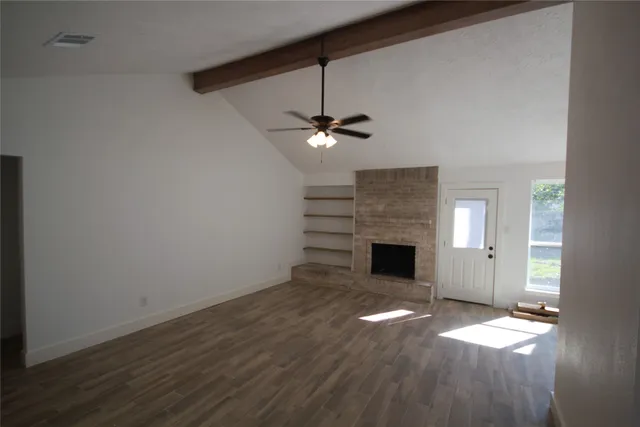 an empty room with a fireplace and wooden floor