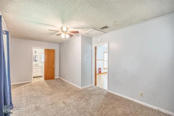 an empty room with a bathroom and a chandelier fan