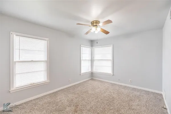 a view of an empty room and chandelier fan