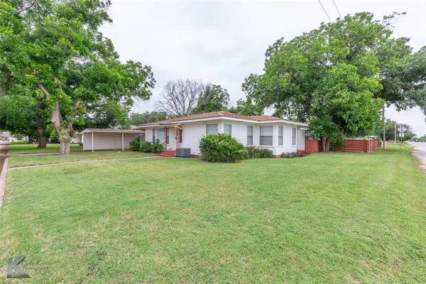 a front view of a house with a yard and trees