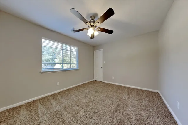 an empty room with ceiling fan and window