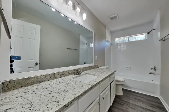 a bathroom with a granite countertop sink a toilet and shower
