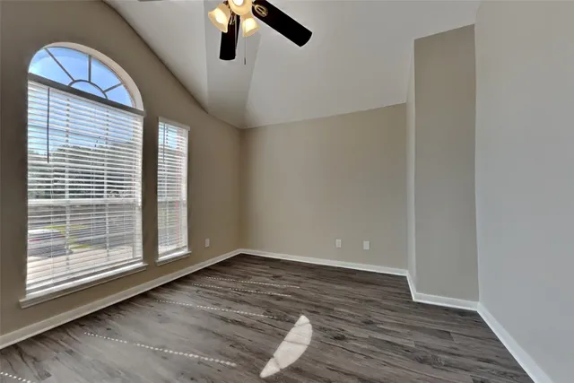 a view of an empty room with wooden floor and window