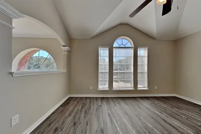 a view of an empty room with wooden floor and a window