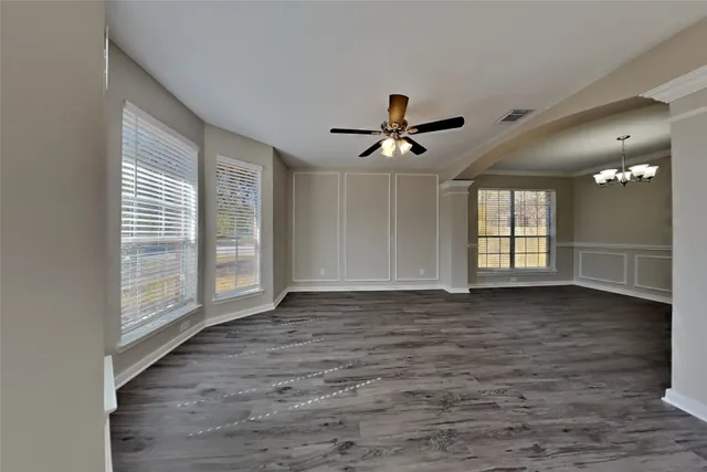 a view of an empty room with a window and wooden floor