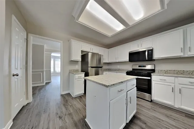 a kitchen with a microwave a stove a sink dishwasher a refrigerator and cabinets with wooden floor