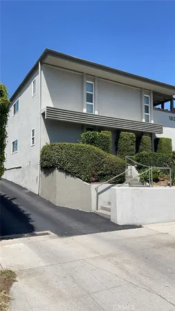 a front view of a house with garage and plants