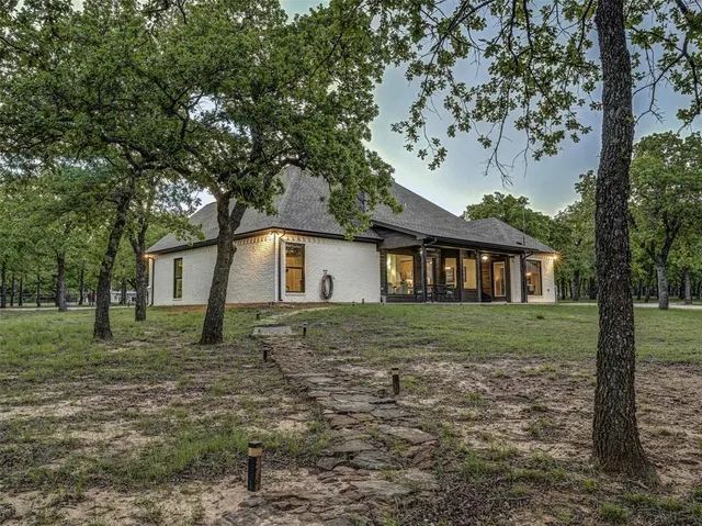 a view of a yard in front of a house with a large tree