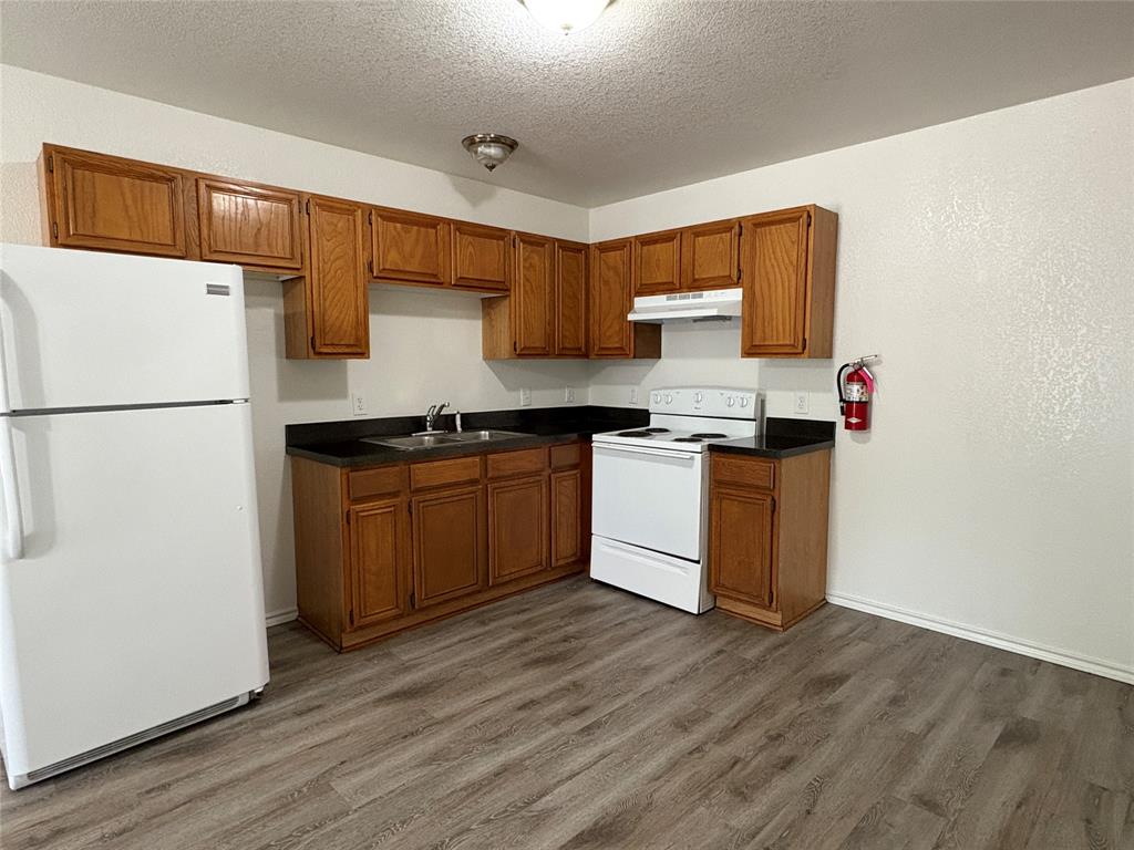 404 South Anglin Street, Unit B Cleburne, TX 76031 - Photo 1 of 12 a kitchen with stainless steel appliances granite countertop a stove a sink dishwasher and a refrigerator