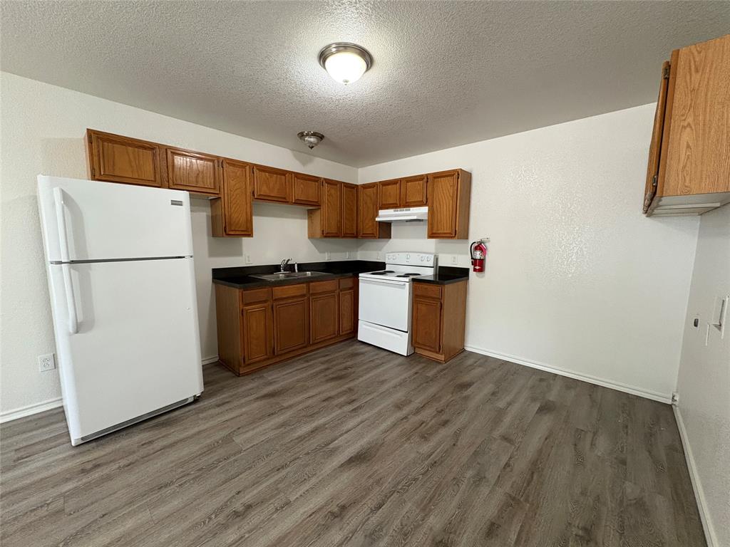 404 South Anglin Street, Unit B Cleburne, TX 76031 - Photo 2 of 12 a kitchen with a refrigerator and a stove top oven