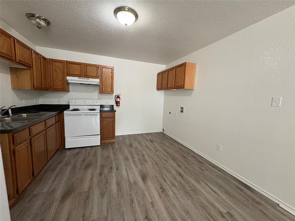 404 South Anglin Street, Unit B Cleburne, TX 76031 - Photo 8 of 12 a kitchen with a wooden floor and a stove top oven