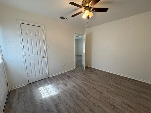 an empty room with wooden floor fan and windows