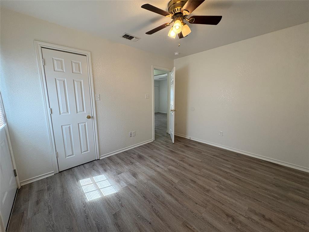 404 South Anglin Street, Unit B Cleburne, TX 76031 - Photo 9 of 12 an empty room with wooden floor fan and windows