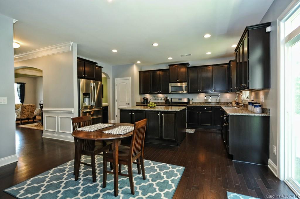 4002 Fallondale Road Waxhaw, NC 28173 - Photo 8 of 24 a kitchen with stainless steel appliances kitchen island granite countertop a sink a stove a dining table and chairs