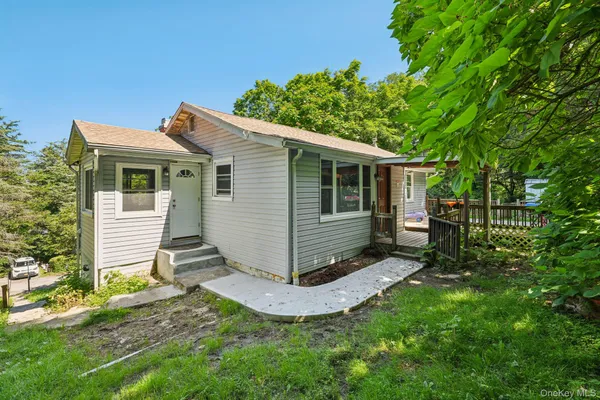 a view of a house with a yard plants and large tree