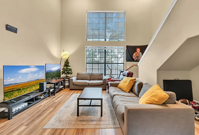 a living room with furniture a flat screen tv and a floor to ceiling window