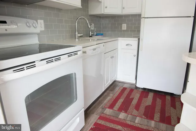 a kitchen with granite countertop white cabinets and white appliances