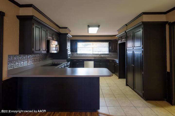 3313 Lombard Road Amarillo, TX 79106 - Photo 6 of 20 a kitchen with kitchen island granite countertop a sink and a refrigerator