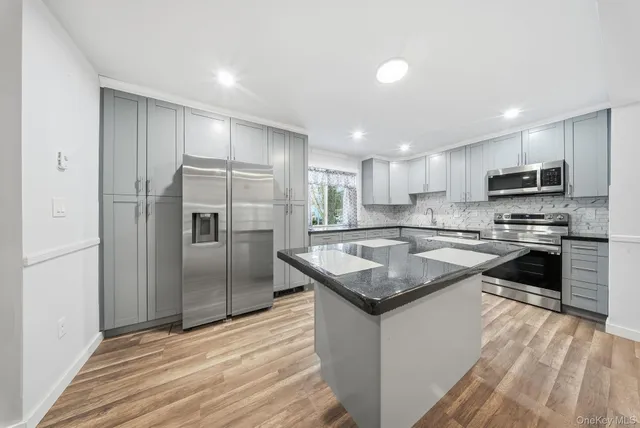 a kitchen with kitchen island granite countertop a sink appliances and cabinets