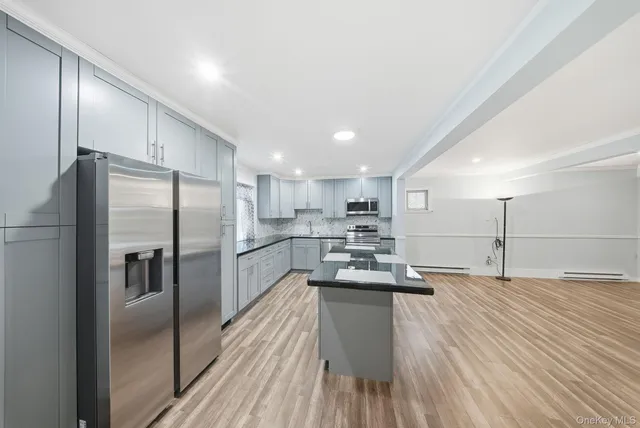 a kitchen with kitchen island a counter top space a refrigerator a sink and a stove